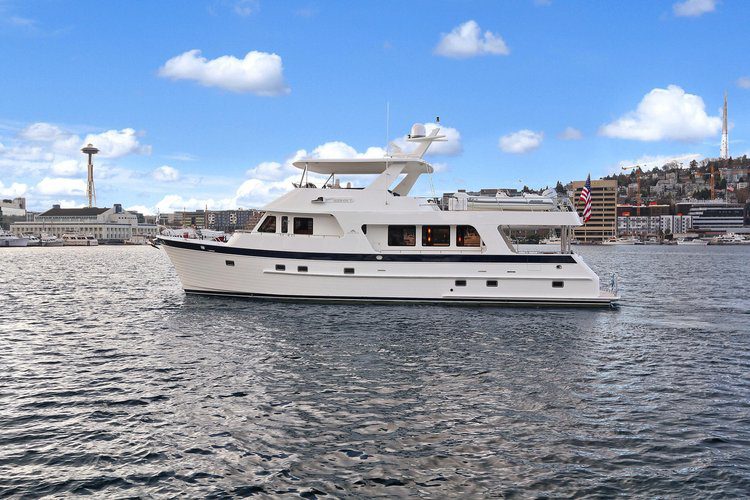 Luxury yacht cruising on water, featuring a spacious white hull and upper deck, with city skyline in the background, representing premium yacht rental options for events at Happiest Ours.