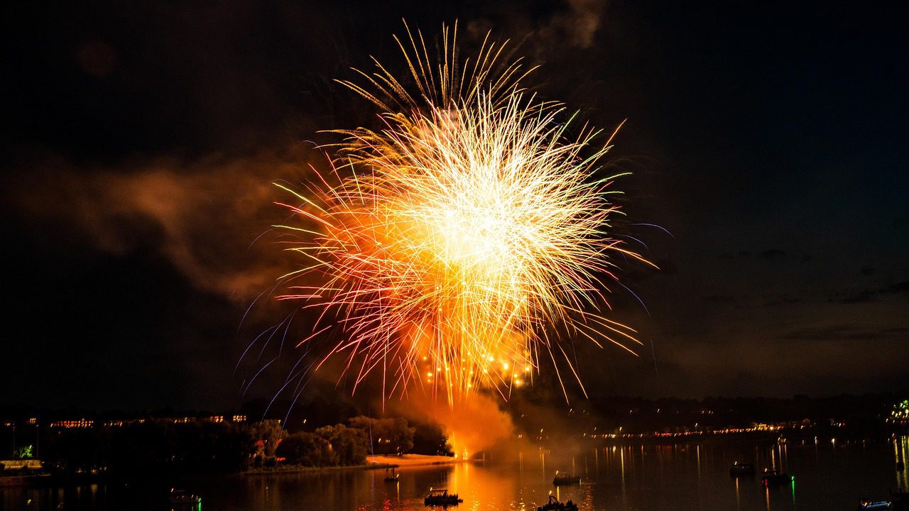 Fireworks exploding in a night sky over a marina, celebrating the 4th of July, with boats illuminated in the foreground, highlighting festive yacht rental opportunities in Southern California.